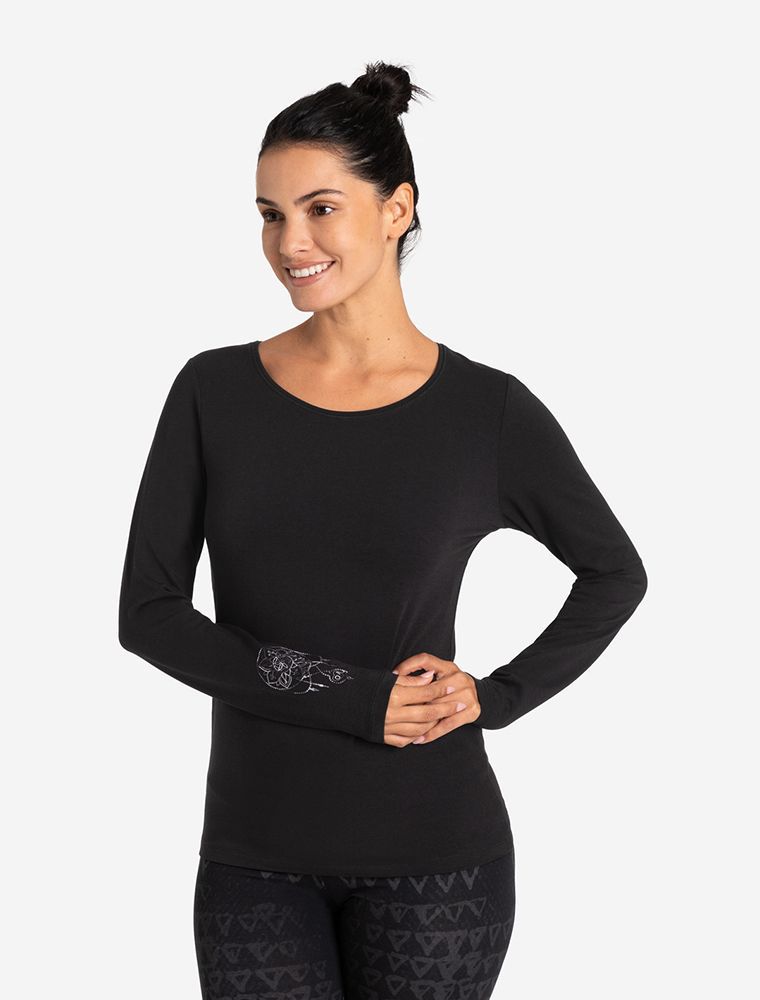 Frau in elegantem Langarm Shirt in schwarz. Im Fokus steht die raffinierte Stickerei am Arm in Grautönen.