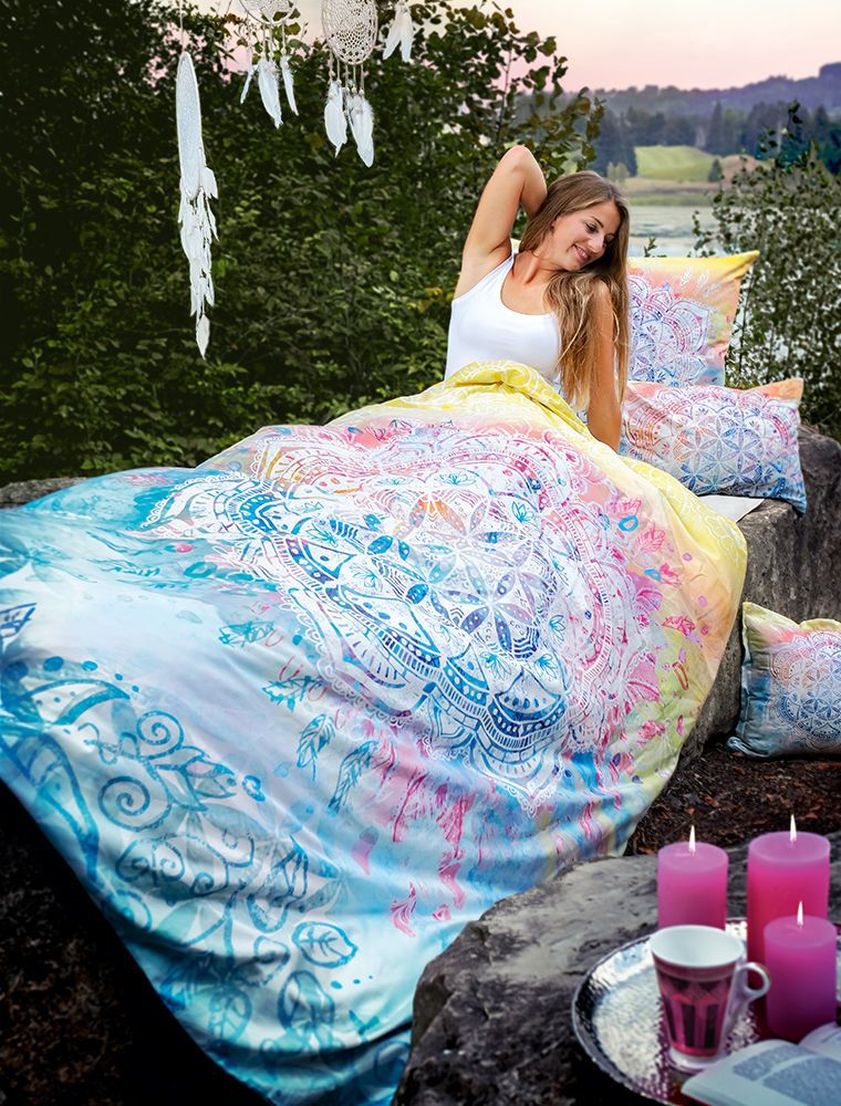 Frau in der Bettwäsche Beauty Dream in bezaubernden, bunten Farben. Draußen in der Natur, auf einem großen Stein. Morgens bei Sonnenaufgang am See.