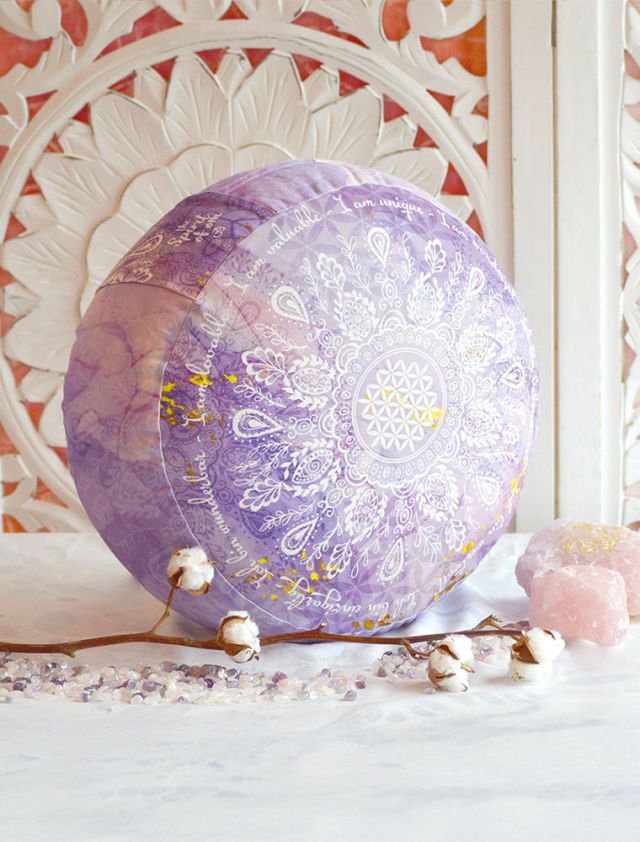 Rundes Meditationskissen in der Farbe Flieder. Schöne, florale Muster mit einem Friedenszeichen in der Mitte. Das Kissen steht aufrecht auf weißem Hintergrund.
