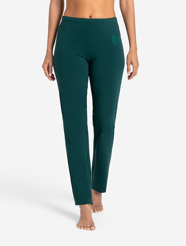Links Frau, rechts Mann sitzen auf weißen Paletten. Bambus Oberteile und Wellnesshosen aus Bio-Baumwolle in farngrün. Hose Unisex. Blume des Lebens auf der Hüfte. Sporthose, Yogahose, Jogginghose. Fair hergestellt von The Spirit of OM.