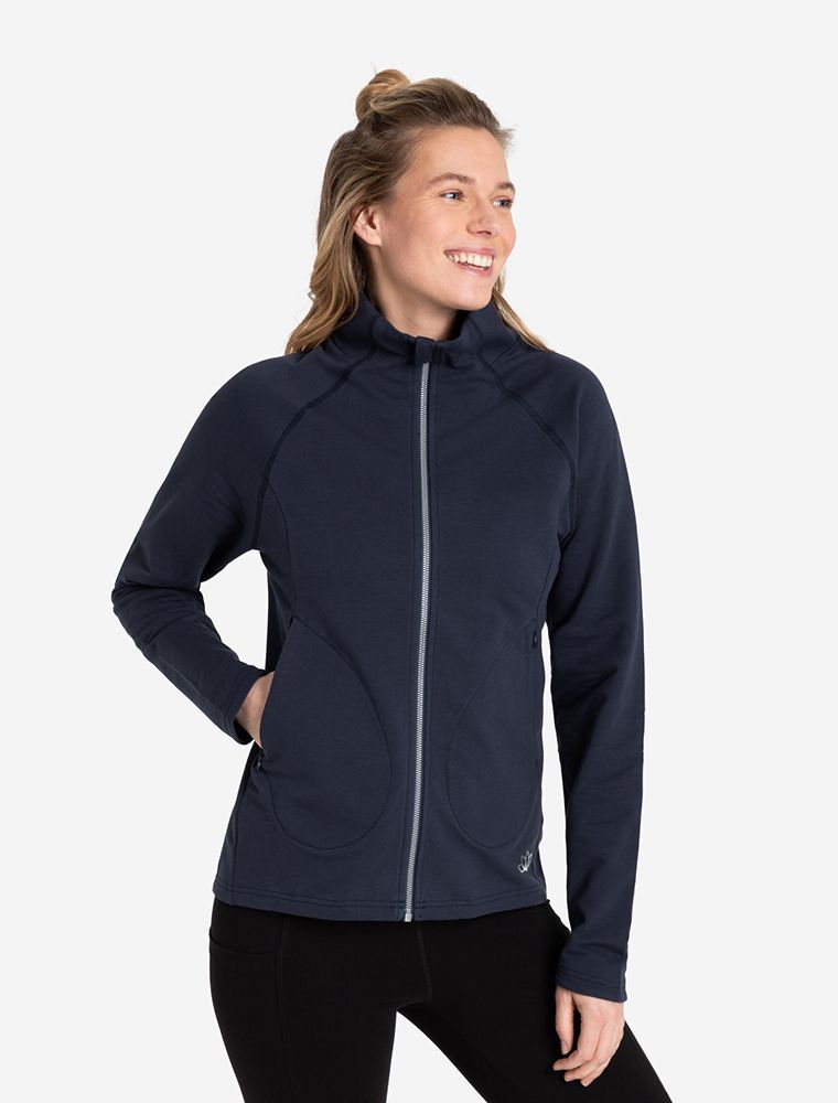 Frau mit Reißverschluss Jacke. Elegante Kombination aus Sweatjacke dunkelblau mit schwarzer Leggigns. Die Jacke hat einen Reißverschluss und ist geschlossen.