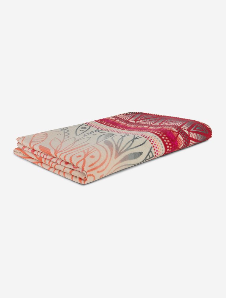 Herrlich kuchelige Plaid-Decke aus Bio-Baumwolle ausgebreitet auf einem Hängestuhl. In der Mitte sieht man die Blume des Lebens, umrahmt von einem Mandala in pink rot orange und grau.